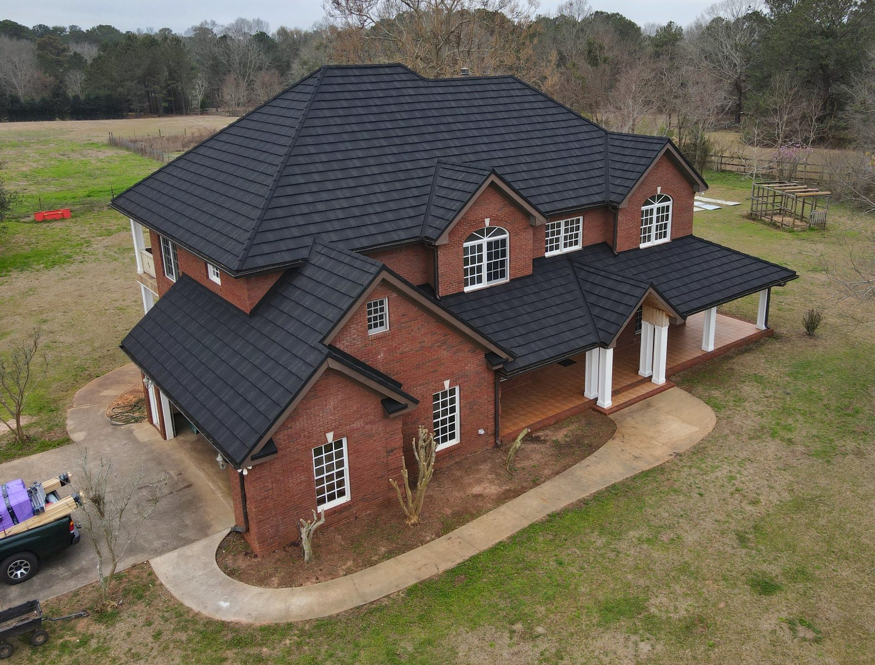 Aerial view of a black stone-coated steel roof on a two-story brick home